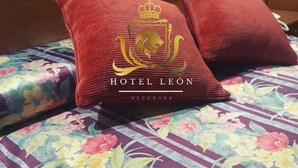 Llits amb un estovat estampat de flors i dos coixins vermells amb un logotip amb cresta.