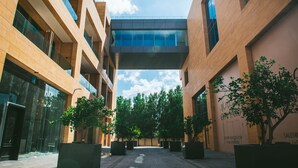 Een modern gebouw met een centraal glazen atrium, omgeven door bomen en potplanten.