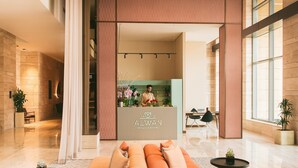Een moderne lobby met een receptiebalie, een zithoek en grote ramen.