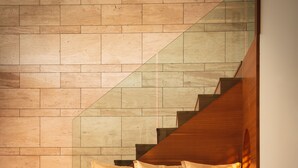 Een modern interieur met een houten trap, een bankje en een kleine tafel.