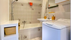 A modern bathroom with a bathtub, shower, and two sinks.