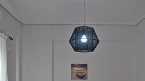 Een netjes opgemaakt bed met een grijs hoofdbord, een nachtkastje met een lamp en een schilderij aan de muur.