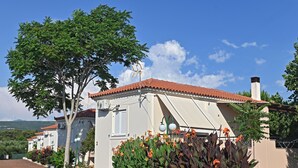 Een villa met een rode tegelsdak, witte muren en een tuin met oranje bloemen.