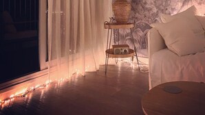 Una habitación con puerta corrediza de vidrio, una mesa redonda, un sofá, una lámpara y un mural en la pared.