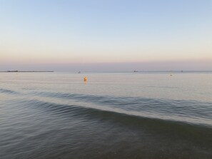 A calm sea with gentle waves, a distant shoreline, and a few buoys.