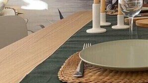 Una mesa de comedor dispuesta con un posavasos, un plato, cubiertos y velas.