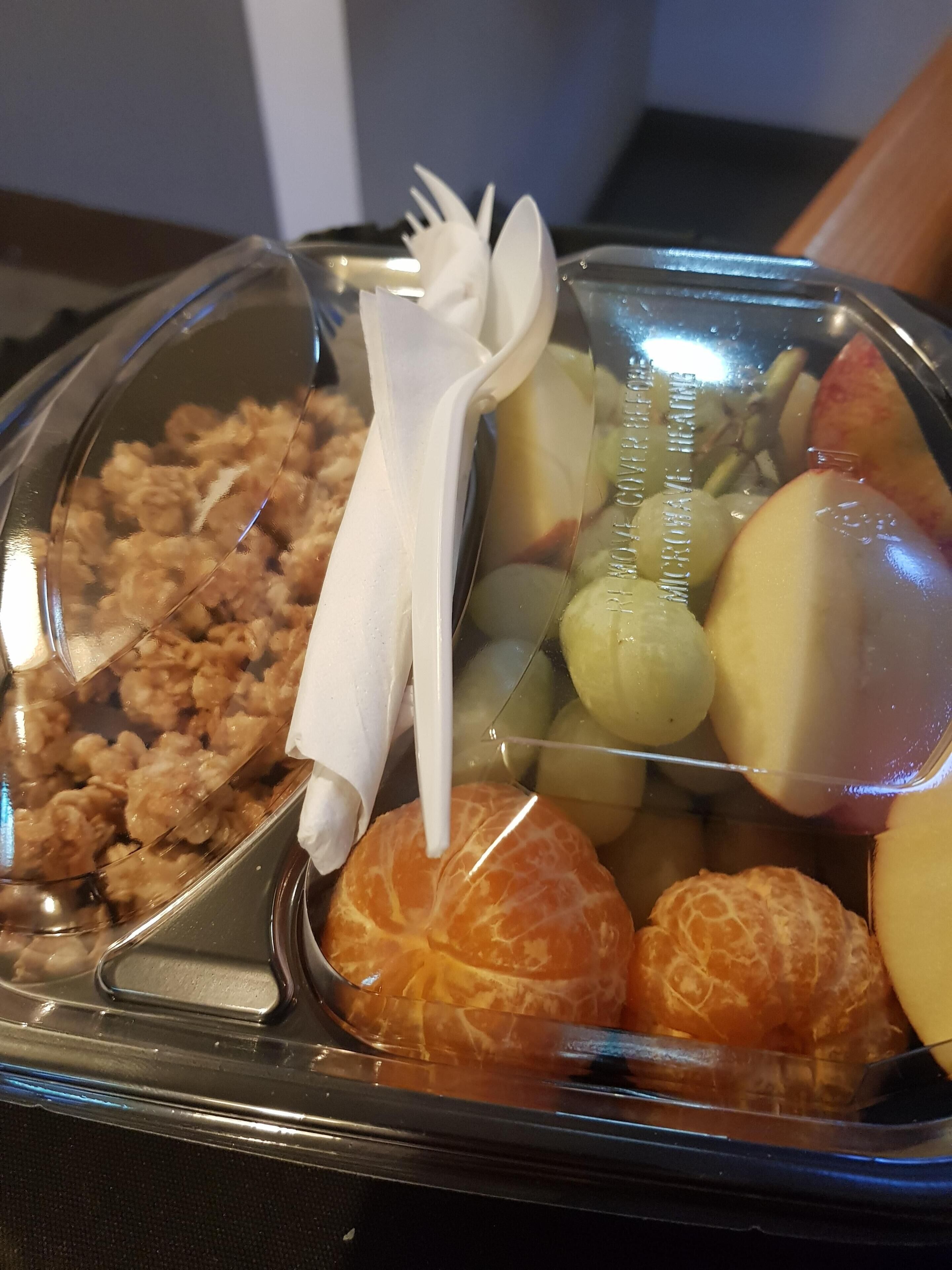 A meal tray with fruits, nuts, and a plastic fork and spoon.