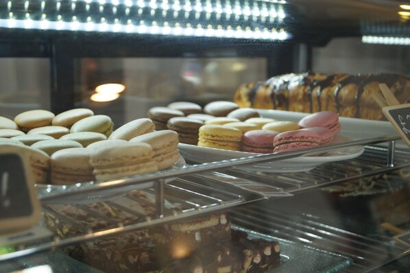 A display case with various baked goods including macarons and a chocolate-covered pastry. - The Narrows Guesthouse (Portaferry)