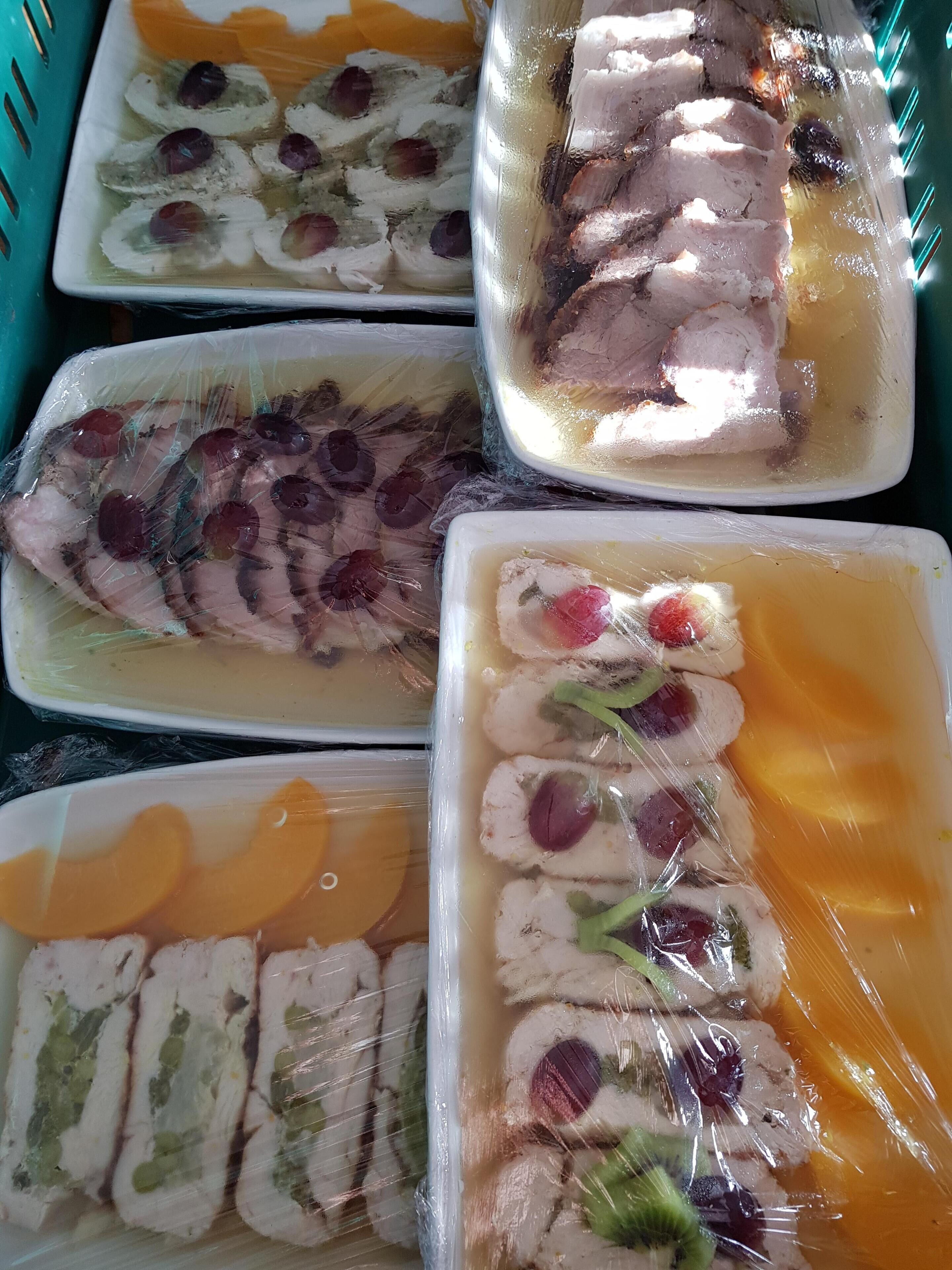 Divers produits alimentaires, notamment des viandes et des fruits coupés en tranches, présentés dans des récipients en plastique.