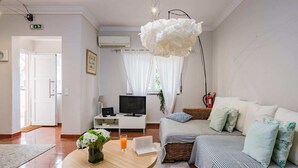 A modern living room with a sofa, TV, and a dining table with a vase of flowers.