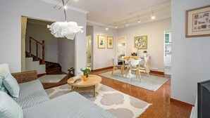 A spacious living area with a dining table, a sofa, and a staircase.
