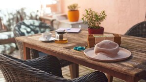 A wooden table with a woven basket, a hat, a cup, a jar, and a potted plant.