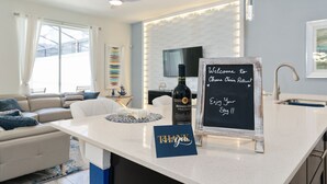 Una cocina moderna con encimera blanca, una botella de vino, un cartel de pizarra y una tarjeta de agradecimiento.
