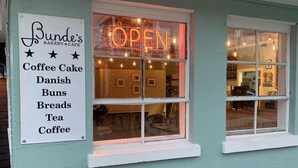 A building with a sign listing items like coffee cake, Danish buns, and tea.