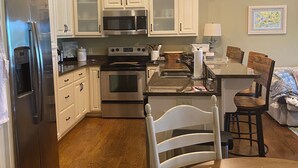 A modern kitchen with white cabinets, stainless steel appliances, and a wooden dining table. - Lake side condo nearThe University of Alabama (Northport)