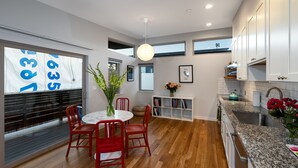 A modern kitchen with white cabinets, a granite countertop, and a dining area with red chairs and a round table. - lower west side style & quality 1BR (Santa Cruz)