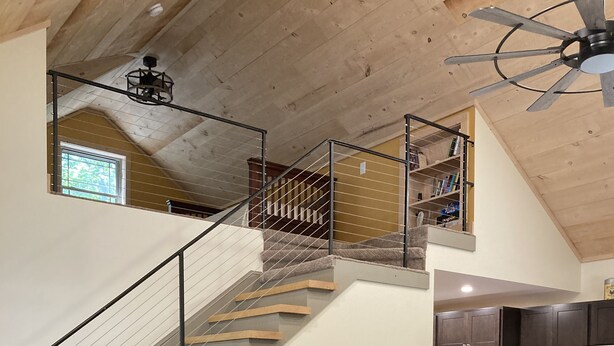 A spacious living area with a brown sofa, wooden coffee table, and a staircase leading to an upper level.