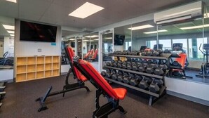 A gym with exercise equipment, mirrors, and a television. - Long Beach 2-301 - 2322067 (Panama City Beach)