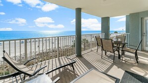 A balcony with a view of the beach and ocean, featuring a table and chairs. - Long Beach 2-301 - 2322067 (Panama City Beach)