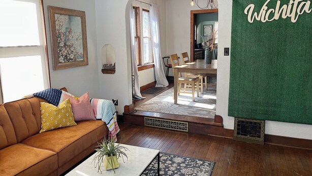 Un salon chaleureux avec un canapé marron, une table basse et un coin repas comprenant une table et des chaises en bois.