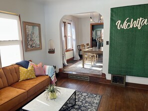 Una sala de estar acogedora con un sofá marrón, una mesita de centro y un comedor con una mesa y sillas de madera.