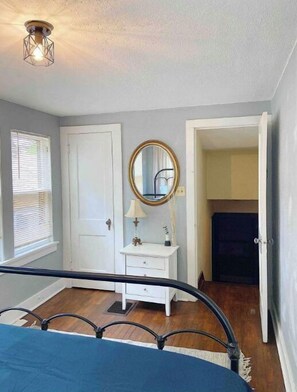 Cozy retreat with a comfortable bed, nightstand, and mirror.