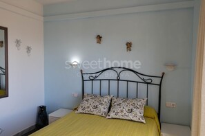 Une chambre à coucher comprenant un lit, deux oreillers, une table de chevet, un miroir et des éléments décoratifs sur les murs.