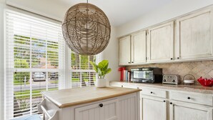 A kitchen with white cabinetry, a wooden countertop, and a hanging wicker light fixture. - Fenced In Backyard! | The Fox Pond (Mount Pleasant)