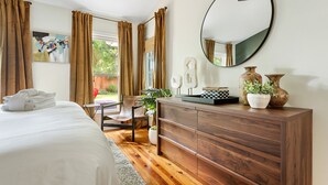 A bedroom with a bed, wooden dresser, and a large mirror. - Fenced In Backyard! | The Fox Pond (Mount Pleasant)