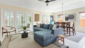 A spacious living room with a sectional sofa, a dining table with chairs, a ceiling fan, and large windows with blinds. - Fenced In Backyard! | The Fox Pond (Mount Pleasant)