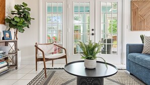 A living room with a round black table, a blue sofa, a wooden chair, and a bookshelf. - Fenced In Backyard! | The Fox Pond (Mount Pleasant)