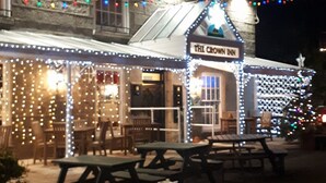 A building with a sign reading "The Crown Inn" and outdoor seating with tables and benches. - Crown Inn (Penzance)