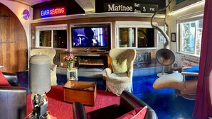 A bar seating area with a television, comfortable seating, and a decorative wall. - 1 of a kind (Astoria)