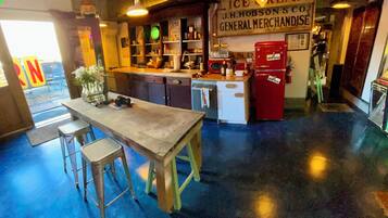 Un espace bar avec des tabourets, un comptoir et une enseigne indiquant « J.H. Hobson & Co., articles de quincaillerie et de marchandises générales ».