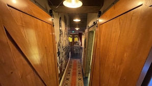 A narrow hallway with wooden walls and a patterned carpet. - 1 of a kind (Astoria)