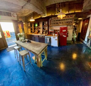 Step into a nostalgic bar area with a central counter and stools, surrounded by vintage decor and exposed beams.