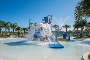 A water park with a water slide, palm trees, and a clear blue sky.