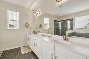 A modern bathroom with a large vanity, dual sinks, and a walk-in shower.