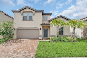 A two-story house with a garage, a well-maintained lawn, and palm trees. - Perfect Location, Beautiful and Spacious 8BD Home, Free Waterpark! #8so884 (Kissimmee)