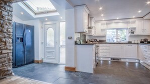 A spacious kitchen with white cabinets, a built-in island, and a skylight. - Sea View - 2 Bedroom Cottage - Wisemans Bridge - Saundersfoot (Saundersfoot)