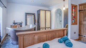 A bedroom with a wooden bed, a bathtub, a wardrobe, and a shower. - Sea View - 2 Bedroom Cottage - Wisemans Bridge - Saundersfoot (Saundersfoot)