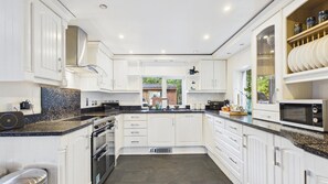 A modern kitchen with white cabinetry, a granite countertop, and a built-in oven.