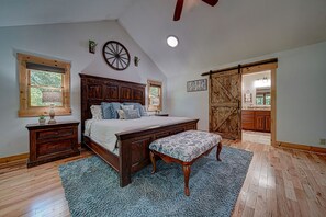 A spacious bedroom with a large bed, wooden headboard, and a rustic barn door closet. - Mt River House Retreat Star5vacations (Ellijay)
