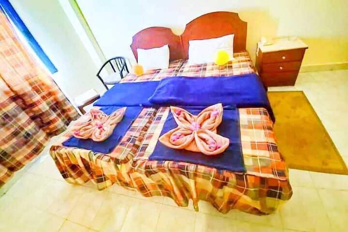 Una cama con una colcha escocesa y dos toallas dobladas en forma de mariposas.