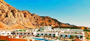 A resort with white buildings, a swimming pool, and a mountainous backdrop. - Amigo Hotel Dahab (Dahab)