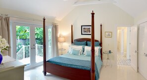 A four-poster bed with a view to a balcony, a bedside table, and a framed picture on the wall. - The Queens Villa (Key West)