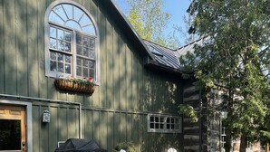 Een houten gebouw met een veranda, buiten zitplaatsen en een hond aan de lijn.