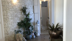 Un pasillo con pared de piedra, plantas en macetas y suelo de baldosas.