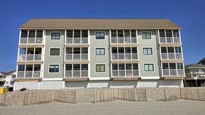 Un immeuble à plusieurs étages, doté de balcons, d’un toit plat et d’une clôture en bois à l’avant.