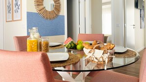 A modern dining area with a glass table, red upholstered chairs, and a blue and beige wall.